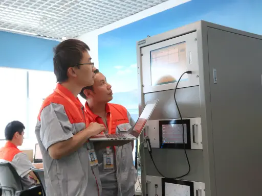 Two engineers checking an analyzer cabinet at a test station