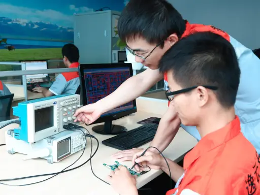 Two engineers debugging a circuit board with an oscilloscope