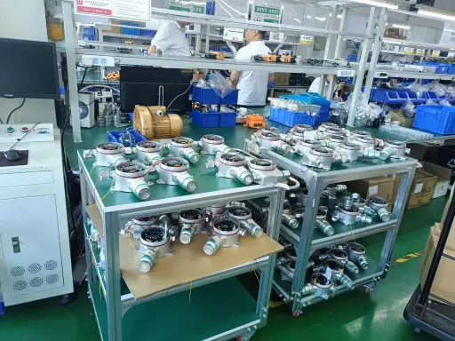 Fixed gas detector housings on assembly carts beside a production line