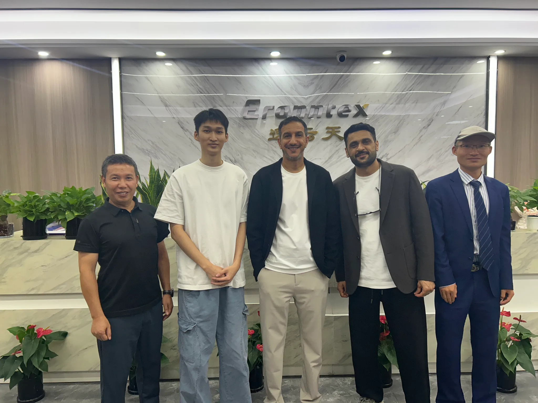 Eranntex team members and visitors from Oman in front of the Eranntex reception sign.