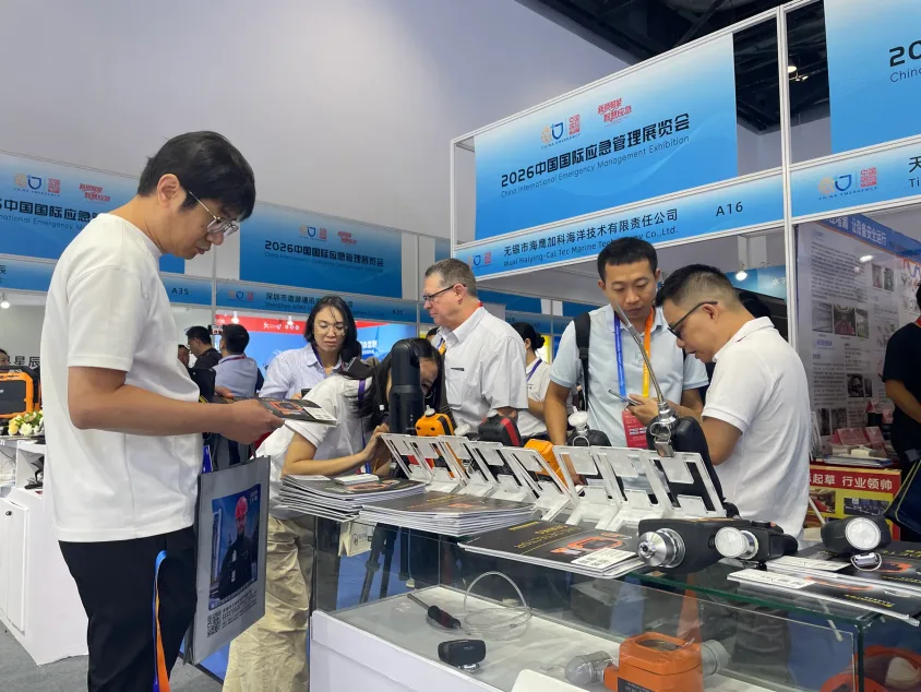 Visitors examining gas detection instruments and product literature at an exhibition counter
